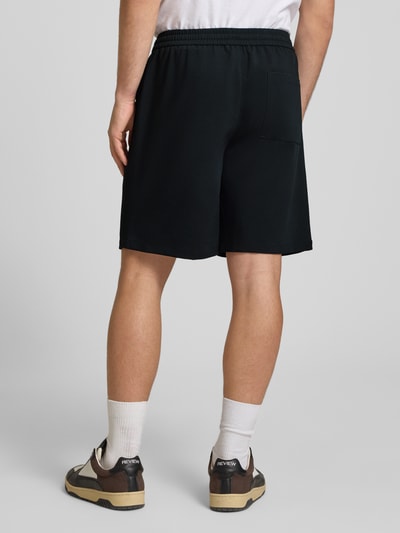 Männermodel trägt Loose Fit Shorts mit elastischem Bund Modell 'WILL' von Only & Sons, Optik: Unifarben, Passform: Loose-Fit, Bundfalte, Bundabschluss: Elastisch mit Tunnelzug, Eingrifftaschen, Gesäßtasche, Ganzkörperansicht Rückansicht.