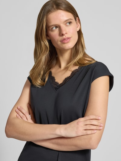 Frauenmodel trägt Relaxed Fit T-Shirt aus Modal-Mix Modell 'KAMALA LACE' von Pieces, unifarben, Spitzenbesatz, V-Ausschnitt, Kurzarm, Nahaufnahme Oberkörper.