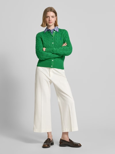 Frauenmodel trägt Regular Fit Strickjacke aus reiner Baumwolle von Polo Ralph Lauren in Optik: Unifarben/strukturiert mit Logo-Stitching, einreihiger Knopfleiste, Rundhals und langarm, Ärmelabschluss gerippt, Materialverarbeitung Zopfstrick, Material reine Baumwolle, Ganzkörperansicht von vorne.