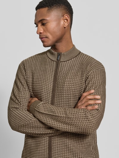 Männermodel trägt Strickjacke mit Woll-Anteil von Emporio Armani in Braun, strukturierte Oberfläche, Stehkragen, Nahaufnahme Oberkörper. Material-Mix mit Lyocell und Wolle, Zweiwege-Reißverschluss, elastische Abschlüsse, gerade Passform.