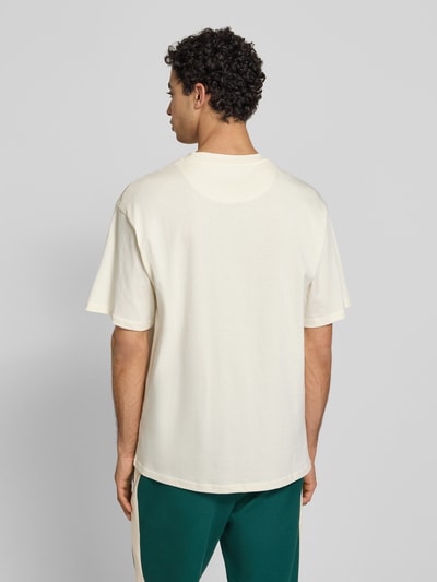Männermodel trägt T-Shirt mit Label-Stitching und Rundhalsausschnitt von KARL KANI, Relaxed-Fit, Reine Baumwolle, Rückenlänge 70 cm, Ganzkörperansicht Rückansicht.