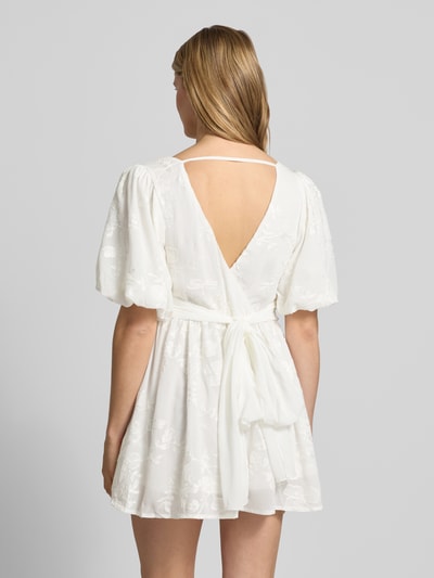 Frauenmodel trägt Minikleid mit Ballonärmeln von Gina Tricot in Weiß mit Embroidery Design, Taillierter Schnitt, Rückenlänge 80 cm, Rückansicht.