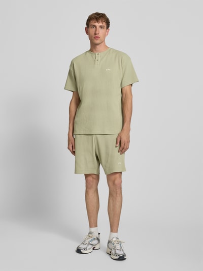 Männermodel trägt Henley-Shirt mit Strukturmuster und Label-Stitching von BLKVIS aus Reine Baumwolle, Regular-Fit, Rundhalsausschnitt, Knopfleiste, Farbe Hellgrün, Ganzkörperansicht von vorne.