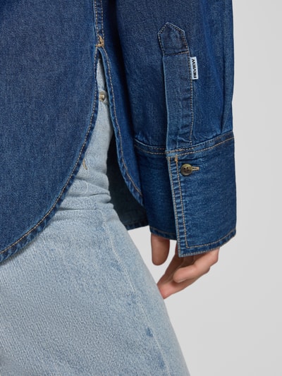 Frauenmodel trägt Oversized Jeansbluse mit Brusttasche von REVIEW aus reiner Baumwolle in kräftigem Blau, Detailaufnahme Ärmel und Saum.