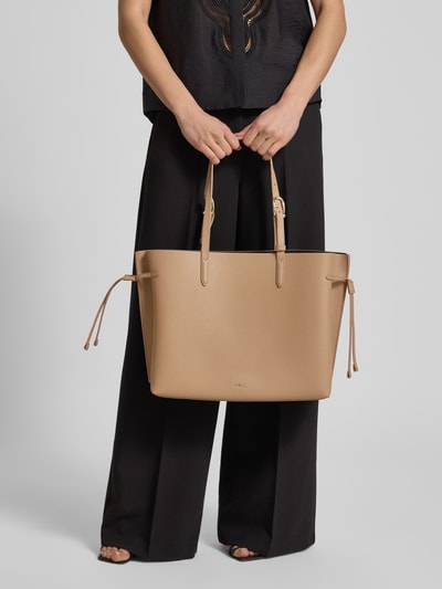 Frauenmodel trägt Tote Bag mit Logo-Applikation Modell 'Ava' von FURLA in Beige, offene Struktur, verstellbare Schulterriemen, Ganzkörperansicht von vorne, Breite 45 cm, Länge 29 cm, Tiefe 14 cm, Riemenlänge 56 cm, mit Reißverschlussfach auf der Innenseite.