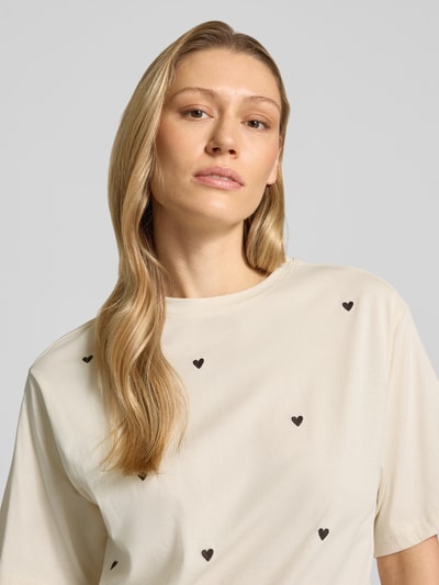 Kobiece modelka nosi T-Shirt mit 1/2-Arm von Jake*s Casual z bawełny, luźny krój, okrągły dekolt, rękaw o dł. 1/2, jasny kolor z czarnymi sercami, długość tyłu w rozmiarze S: 55 cm, zbliżenie na górną część ciała