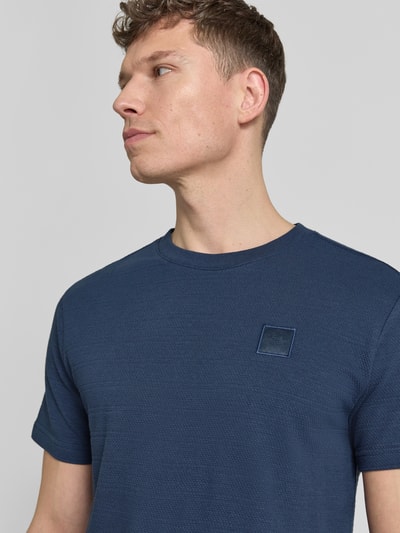 Męski model nosi T-Shirt mit Rundhalsausschnitt od PME Legend, bawełna, krój regular fit, naszywka z logo, kolor granatowy, okrągły dekolt, długość tyłu w rozmiarze M: 69 cm, zbliżenie na górną część ciała