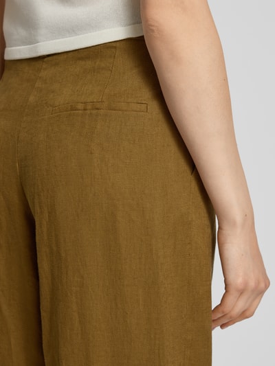 Frauenmodel trägt Straight Fit Leinenhose mit Bügelfalten Modell 'Tempoli' von Mango in Braun, reine Leinen, Detailaufnahme Rückansicht.