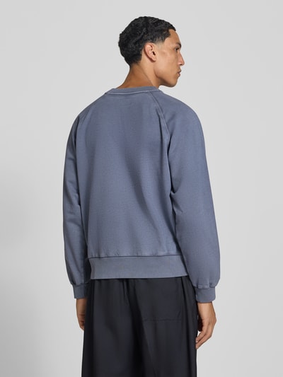 Männermodel trägt Sweatshirt aus reiner Baumwolle von Officine Générale in Blau mit Rundhalsausschnitt und Raglanärmeln, lockere Passform, Ganzkörperansicht Rückansicht. Rückenlänge bei Größe M 60 cm, elastische Abschlüsse.