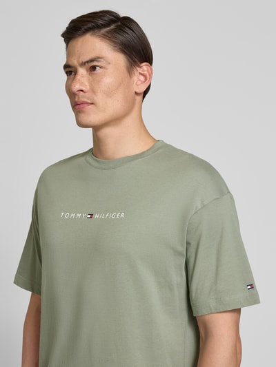 Männermodel trägt Regular Fit T-Shirt mit Label-Schriftzug aus reiner Baumwolle von Tommy Hilfiger in Optik: Unifarben, Nahaufnahme Oberkörper.