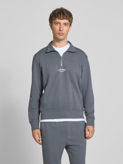 Männermodel trägt Regular Fit Sweatshirt aus Baumwoll-Mix Modell 'Soho' von JACK & JONES in Grau mit Troyer-Kragen, Ganzkörperansicht von vorne.