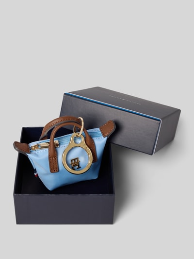 Produktfoto, Schlüsselanhänger im Henkeltaschen-Design von Tommy Hilfiger in hellblau mit braunen Details, goldfarbener Logo-Applikation aus Metall, unifarbene Optik, Reißverschluss, glatte Textur, präsentiert in blauer Box