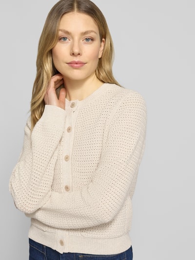 Frauenmodel trägt Regular Fit Strickjacke mit aufgesetzten Taschen Modell 'Biaphy' von Drykorn aus Reine Baumwolle in Beige, Rundhalsausschnitt, Knopfleiste, elastische Abschlüsse, weiche Textur, Ganzkörperansicht von vorne. Rückenlänge bei Größe S: 50 cm, Ärmellänge bei Größe S: 65 cm.