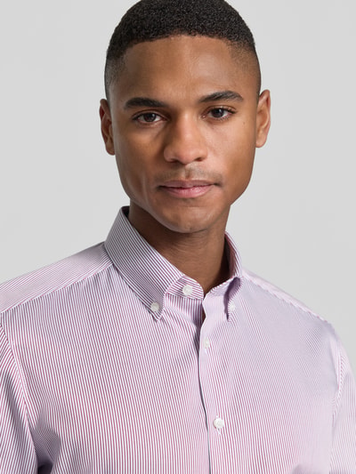 Männermodel trägt Slim Fit Business-Hemd mit Button-Down-Kragen von OLYMP Level Five aus reiner Baumwolle, Nahaufnahme Oberkörper. Schulterbreite 42 cm, Rückenlänge 70 cm, Ärmellänge 67 cm, feines Streifenmuster, dezente Farbgebung, sichtbare Knopfleiste.