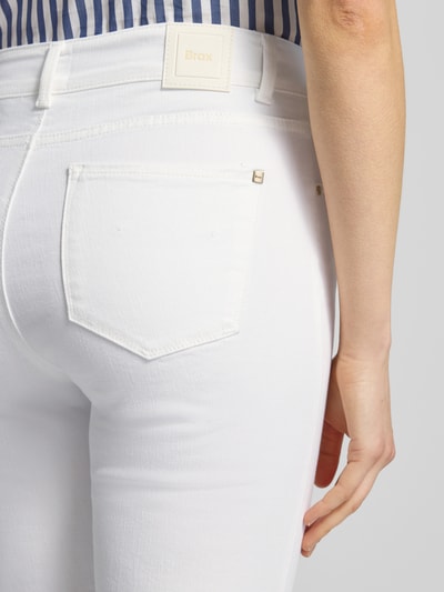 Frauenmodel trägt Bootcut Jeans mit Fransen Modell 'SHAKIRA' von Brax aus weißem Baumwoll-Mix mit Stretch, Nahaufnahme Rückansicht.