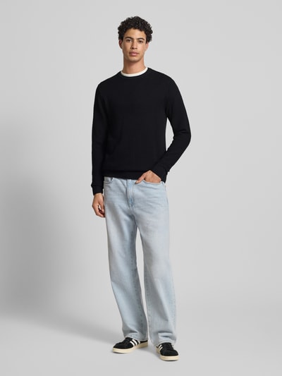 Männermodel trägt Strickpullover mit Rundhalsausschnitt Modell 'OTTO' von JACK & JONES in Schwarz mit Strukturmuster, Reine Baumwolle, Regular-Fit, Ganzkörperansicht von vorne.