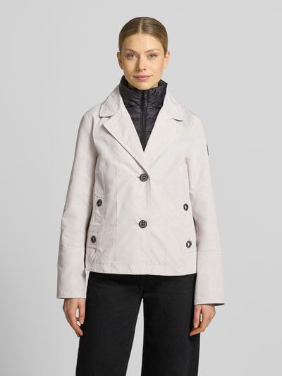 Modelka kobieca ma na sobie Jacke im 2-in-1-Look od Amber & June, jasna, krój regular fit, detal z logo, guzik, długość tyłu 65 cm, szerokość w rozmiarze 36: 42 cm ramion, 51 cm biustu, długość rękawa 63 cm, widok całej sylwetki z przodu.