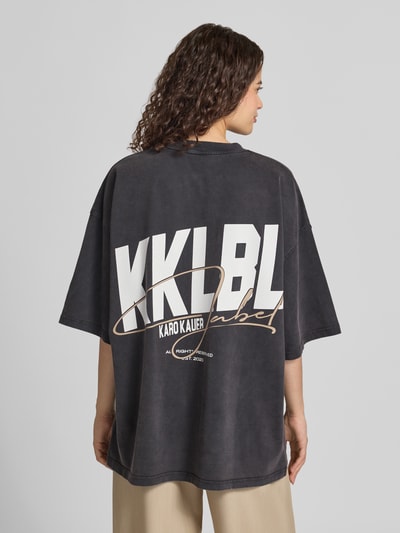 Vrouwenmodel draagt Oversized T-Shirt mit Label-Print van Karo Kauer in puur katoen, zwarte kleur, ronde hals, ruglengte maat S 72 cm, Ganzkörperansicht Rückansicht.