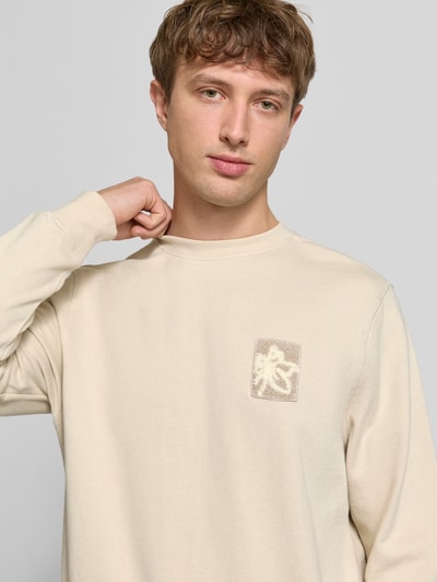 Männermodel trägt Regular Fit Sweatshirt mit floraler Applikation Modell 'Felica' von Blend in Beige, Reine Baumwolle, Nahaufnahme Oberkörper.