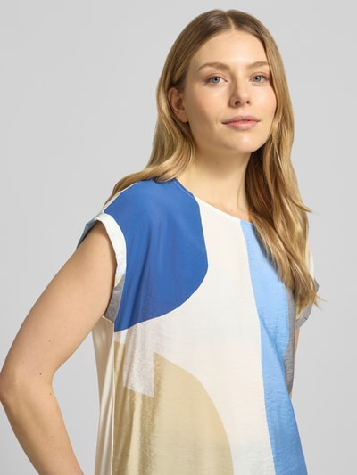 Modelka kobieca nosi Regular Fit T-Shirt aus Viskose-Mix od s.Oliver RED LABEL, wzór abstrakcyjny, satynowe wykończenie, w wielokolorowej tonacji, dekolt w łódkę, krótki rękaw z wywiniętym brzegiem, z aplikacją wyhaftowanego logo, mieszanka wiskozy, zbliżenie na górną część ciała