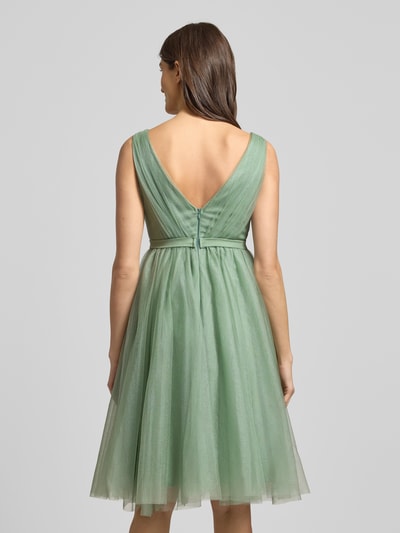 Frauenmodel trägt Cocktailkleid mit V-Ausschnitt von TROYDEN COLLECTION in Unifarbe, tailliert, breite Träger, Rückenansicht, Ganzkörperansicht Rückansicht. Strapazierfähiges Material, Wickel-Optik, Nahtreißverschluss, Rückenlänge 78 cm, Brustweite 47 cm bei Größe 36.