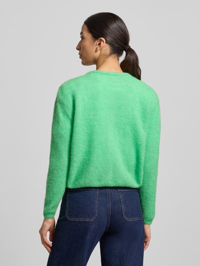 Vrouwenmodel draagt Strickjacke mit Knopfleiste Modell 'VITOW' van American Vintage in lichtgroen, rechte pasvorm, geribde boorden, volledige rugaanzicht.