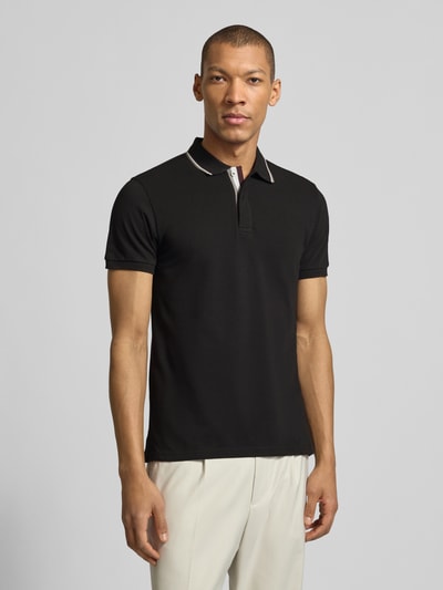 Männermodel trägt Slim Fit Poloshirt aus Baumwolle von Colmar Originals in Schwarz mit Polokragen, Label-Details, Ganzkörperansicht von vorne.