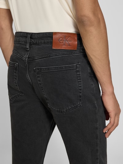 Mężczyzna nosi Slim Fit Jeans aus Baumwoll-Mix von Calvin Klein Jeans, ciemnoszary denim, widok z tyłu, zdjęcie detaliczne.