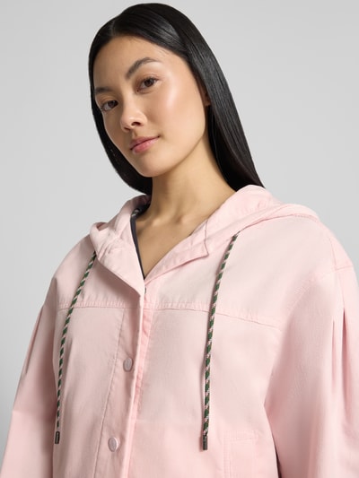 Vrouwenmodel draagt Regular Fit Jacke aus Baumwoll-Mix van Marc Cain in lichtroze met tunnelkoord capuchon, steekzakken, knoopsluiting, elastische mouwboorden, ruglengte bij maat 36: 52 cm, borstwijdte 40 cm, mouwlengte 59 cm, Nahaufnahme bovenlichaam.