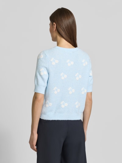 Frauenmodel trägt Slim Fit Strickjacke mit Intarsien Modell 'DOFFY INTARSIA' von Vero Moda in Hellblau, florales Allover-Muster, Rundhals, Kurzarm, gerippte Abschlüsse, Strickmaterial, Optik: Unifarben, Ganzkörperansicht Rückansicht.