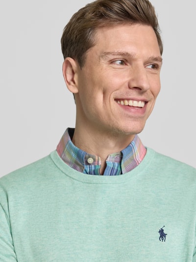 Męski model nosi Slim Fit Pullover aus reiner Baumwolle od Polo Ralph Lauren, miękki dzianinowy materiał, kolor jednolity, logo, okrągły dekolt, widok zbliżenie na górę ciała.