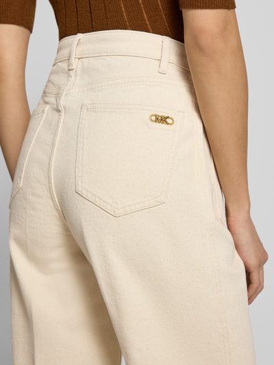 Frauenmodel trägt High Rise Bootcut Fit Stoffhose aus Baumwoll-Mix von MICHAEL Michael Kors in Beige mit Label-Anhänger, Detailaufnahme Rückansicht.