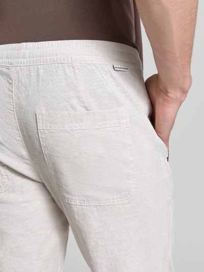 Männermodel trägt Gerade Hose aus Leinen-Baumwoll-Mix von Tom Tailor in look: effen, labelpatch, achterzak, mix van linnen en katoen. Detailaufnahme Gesäßbereich.