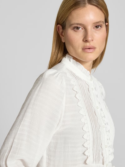 Frauenmodel trägt Regular Fit Bluse mit Stehkragen und Spitze Modell 'Ariel' von Lollys Laundry aus weißem Rayon-Mix, Nahaufnahme Oberkörper. Damen Bluse, Regular-Fit, Stehkragen, Spitze, gelegte Falten, Knopfleiste, Rückenlänge 61 cm, Ärmellänge 31 cm bei Größe S.