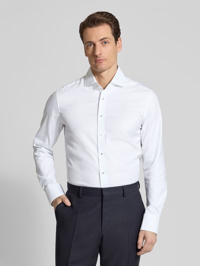 Männermodel trägt Slim Fit Business-Hemd mit Kentkragen von ETERNA, weiße Reine Baumwolle, durchgehende Knopfleiste, Langärmelig, Sportmanschetten, Rückenlänge 80 cm, Schulterbreite 45 cm, Ärmellänge 67 cm, Ganzkörperansicht von vorne.