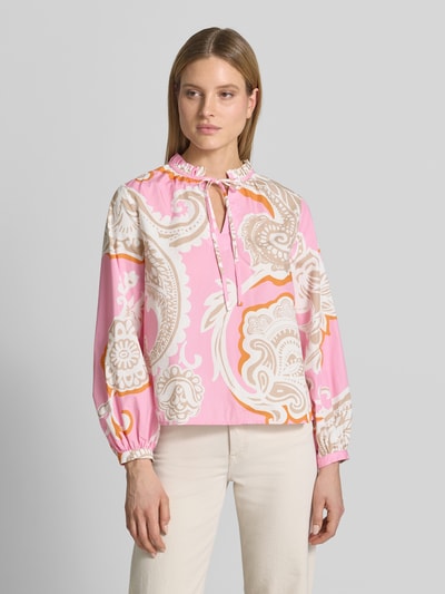 Modelka kobieca nosi Regular Fit Bluse mit Allover-Paisley-Print von Emily Van den Bergh, różowy i beżowy wzór, czysta bawełna, długi rękaw, stójka z falbaną, zapięcie na guzik, szerokie mankiety, widok całej sylwetki z przodu.
