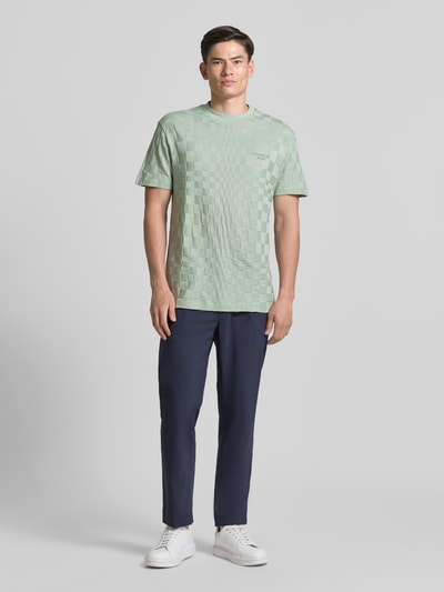 Männermodel trägt mintgrünes Regular-Fit T-Shirt aus reiner Baumwolle Modell 'PS SPIRIT70' BOSS Green X PORSCHE von BOSS, schlichtes Schachbrettmuster, kombiniert mit dunkelblauer Hose, Herren T-Shirt von BOSS Green, Ganzkörperansicht von vorne.