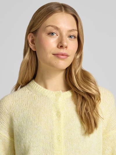 Modelka kobieca nosi kardigan mit Rundhalsausschnitt und Knopfleiste von Luisa Cerano, mieszanka materiałów z domieszką alpaki, krój regular fit, okrągły dekolt, listwa guzikowa, długość tyłu w rozmiarze 36: 56 cm, długość rękawów w rozmiarze 36: 52 cm, jasny żółty odcień, faktura włóczkowa, Nahaufnahme górnej części ciała.