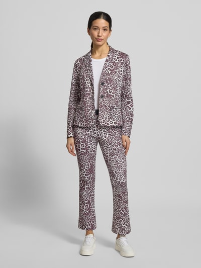 Frauenmodel trägt Flared Fit Stoffhose mit Allover-Animal-Print von Marc Cain, elastisches Material, braun-weiße Muster, Ganzkörperansicht von vorne.
