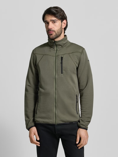 Männermodel trägt Regular Fit Jacke mit Stehkragen Modell 'Berthold' von Icepeak in Oliv mit Napoleontasche, Vorderreißverschluss und elastischen Abschlüssen, Eingrifftaschen mit Reißverschluss, Ganzkörperansicht von vorne. Rückenlänge 74 cm, Schulterbreite 46 cm, Brustweite 52 cm, Ärmellänge 71 cm.