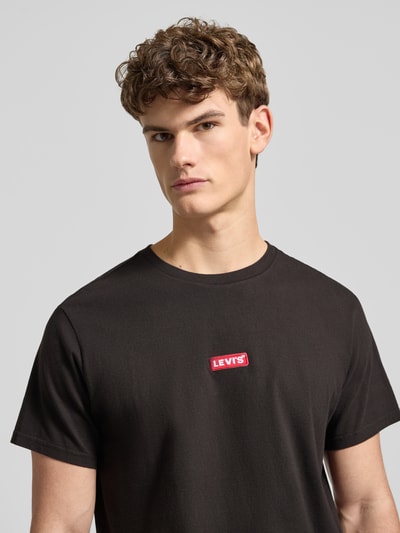 Männermodel trägt T-Shirt mit Label-Detail von Levi's®, schwarz, reine Baumwolle, Relaxed Fit, Nahaufnahme Oberkörper.