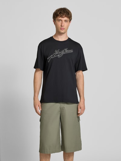 Männermodel trägt Oversized Fit T-Shirt mit Logo-Stitching von KARL KANI aus reiner Baumwolle, Rundhalsausschnitt, Herren T-Shirt, Ganzkörperansicht von vorne