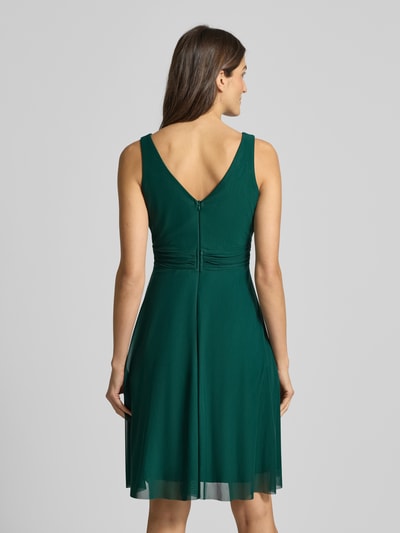 Kobiece model prezentuje zieloną sukienkę Cocktailkleid mit V-Ausschnitt od TROYDEN COLLECTION, taliowany krój, podszewka, widok z tyłu całej sylwetki.