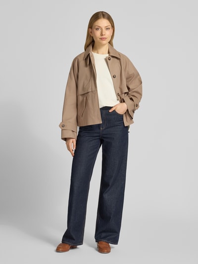 Frauenmodel trägt Jacke mit Ärmelriegeln Modell 'Svada' von MSCH Copenhagen aus reiner Baumwolle, krój regular fit, beżowy kolor, naszywane kieszenie, Szerokość w rozmiarze XS/S: 52 cm, długość tyłu: 58 cm, szerokość ramion: 42 cm, długość rękawa: 63 cm, całkowity widok z przodu.