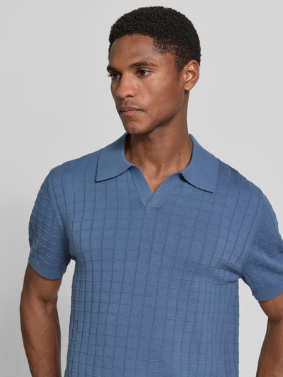 Męski model nosi Regular Fit Poloshirt mit Strukturmuster von Christian Berg Men z bawełny, kołnierzyk polo, dekolt w serek, niebieski, fakturowany wzór, długość tyłu 69 cm, długość rękawów 27 cm, krój regular fit, kolor jednolity, zbliżenie tułowia z przodu.