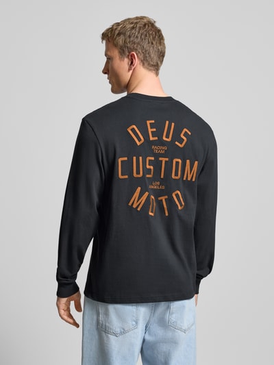 Männermodel draagt Regular Fit Shirt met lange mouwen met logostitching model 'Engineer' van DEUS EX MACHINA, puur katoen, ronde hals, elastische mouwboorden, ruglengte maat M 70 cm, zwart met oranje details, Ganzkörperansicht Rückansicht.