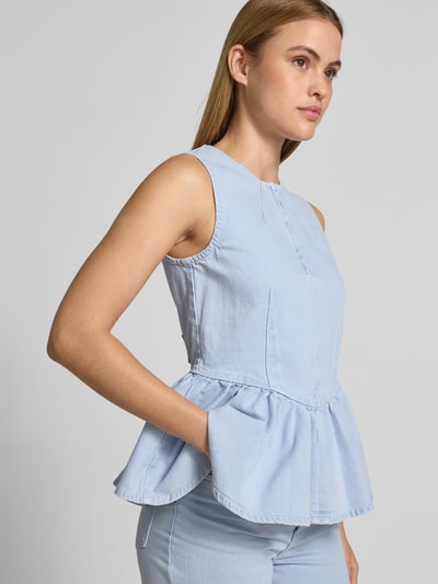 Frauenmodel trägt Slim Fit Top in Denim-Optik von BAUM & PFERDGARTEN, hellblau, Rüschenbesatz, elastischer Baumwoll-Mix, Nahaufnahme Oberkörper.