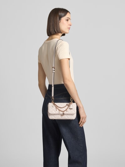 Kobiece modelka nosi torbę na ramię Umhängetasche mit Label-Applikation Modell 'LIBBY' od Guess, jasny kolor, aplikacja z metką, łańcuszki, zapięcie na magnes, główna przegroda, szerokość w rozmiarze 1: 24 cm, długość w rozmiarze 1: 14 cm, głębokość w rozmiarze 1: 6 cm, długość paska na ramię w rozmiarze 1: 114 cm, widok z tyłu na całe ciało