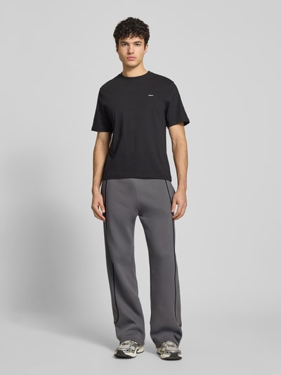 Männermodel trägt Sweatpants mit elastischem Bund und Logo von REVIEW in Grau, Relaxed-Fit, Reine Baumwolle, Ganzkörperansicht von vorne.