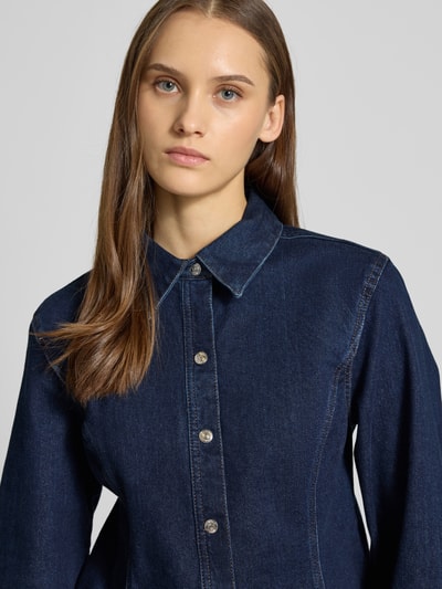 Frauenmodel trägt Regular Fit Jeansbluse Modell 'Classic' von Calvin Klein Jeans in dunkler Denim-Optik, elastischer Baumwoll-Mix, Langärmelig, tailliert, Hemdblusenkragen, durchgängige Knopfleiste, Sportmanschetten, Nahaufnahme Oberkörper.